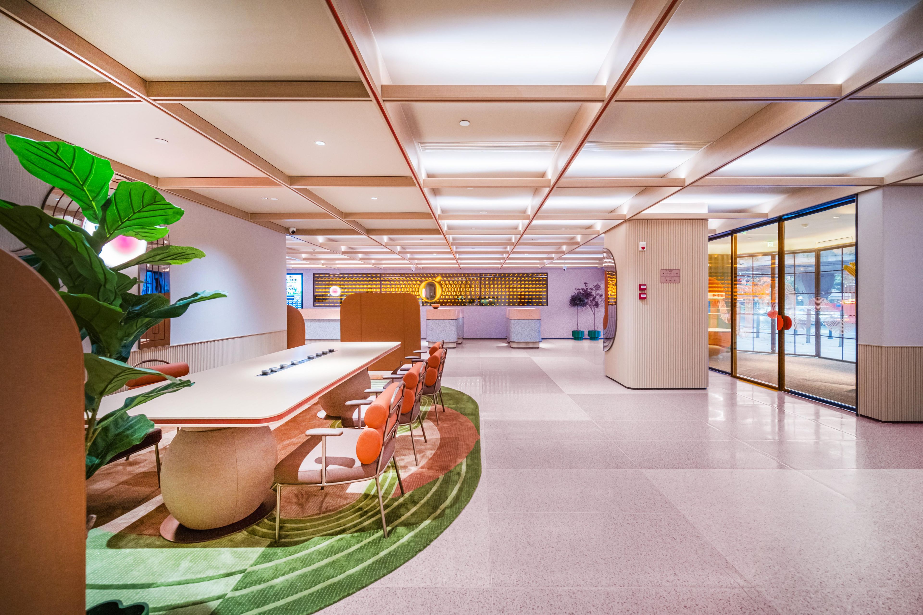 A modern conference room with a long table, chairs, and a large potted plant.
