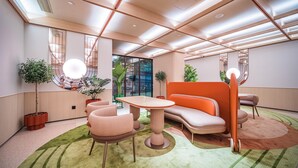A modern interior with a sofa, table, and chairs, a large window, and potted plants. - Orange Hotel Guangzhou Yuexiu Park (Guangzhou)