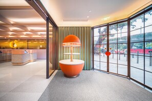 A modern hotel lobby with a reception desk, a unique orange lamp, and large windows offering a view of the street. - Orange Hotel Guangzhou Yuexiu Park (Guangzhou)