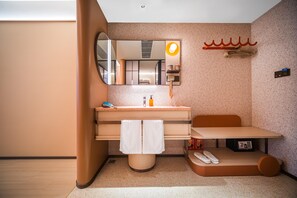 A modern bathroom with a large mirror, a sink with toiletries, a towel rack, and a small table with slippers. - Orange Hotel Guangzhou Yuexiu Park (Guangzhou)