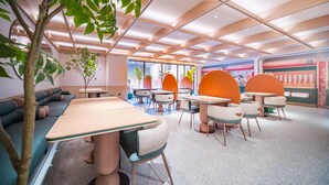 Un interior moderno con una mesa larga, sillas anaranjadas y un sofá verde.