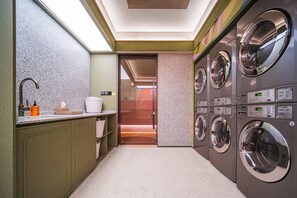 A laundry room with multiple washing machines, a sink, and a towel rack. - Orange Hotel Guangzhou Yuexiu Park (Guangzhou)