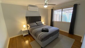 Une chambre moderne avec un lit, des lampes de chevet, un ventilateur de plafond et une fenêtre avec des rideaux.