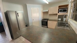 Une cuisine de taille réduite équipée d’un réfrigérateur, d’une cuisinière, d’un four à micro-ondes et d’un évier.