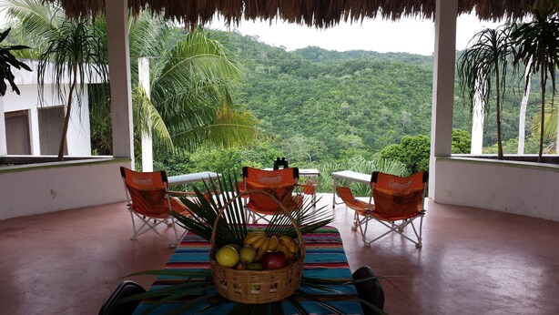 A covered outdoor seating area with a view of a lush green landscape. - Mayan World Adventures (Estero Franco)