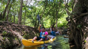 Two people in a yellow kayak on a river surrounded by trees. - Mayan World Adventures (Estero Franco)