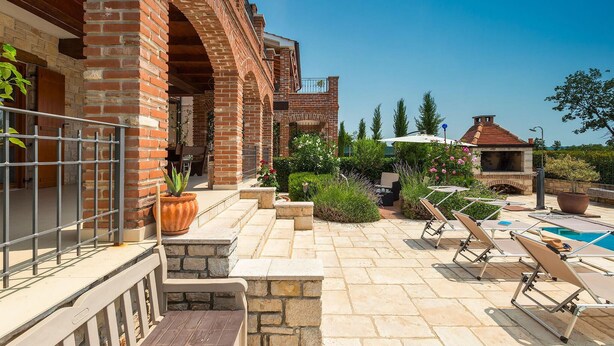 A patio with stone flooring, outdoor furniture, and a brick building with arches. - Awesome home in Kastelir (Kastelir)