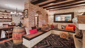 A cozy interior with a brick fireplace, a dining area with wooden chairs, and a patterned rug. - Awesome home in Kastelir (Kastelir)