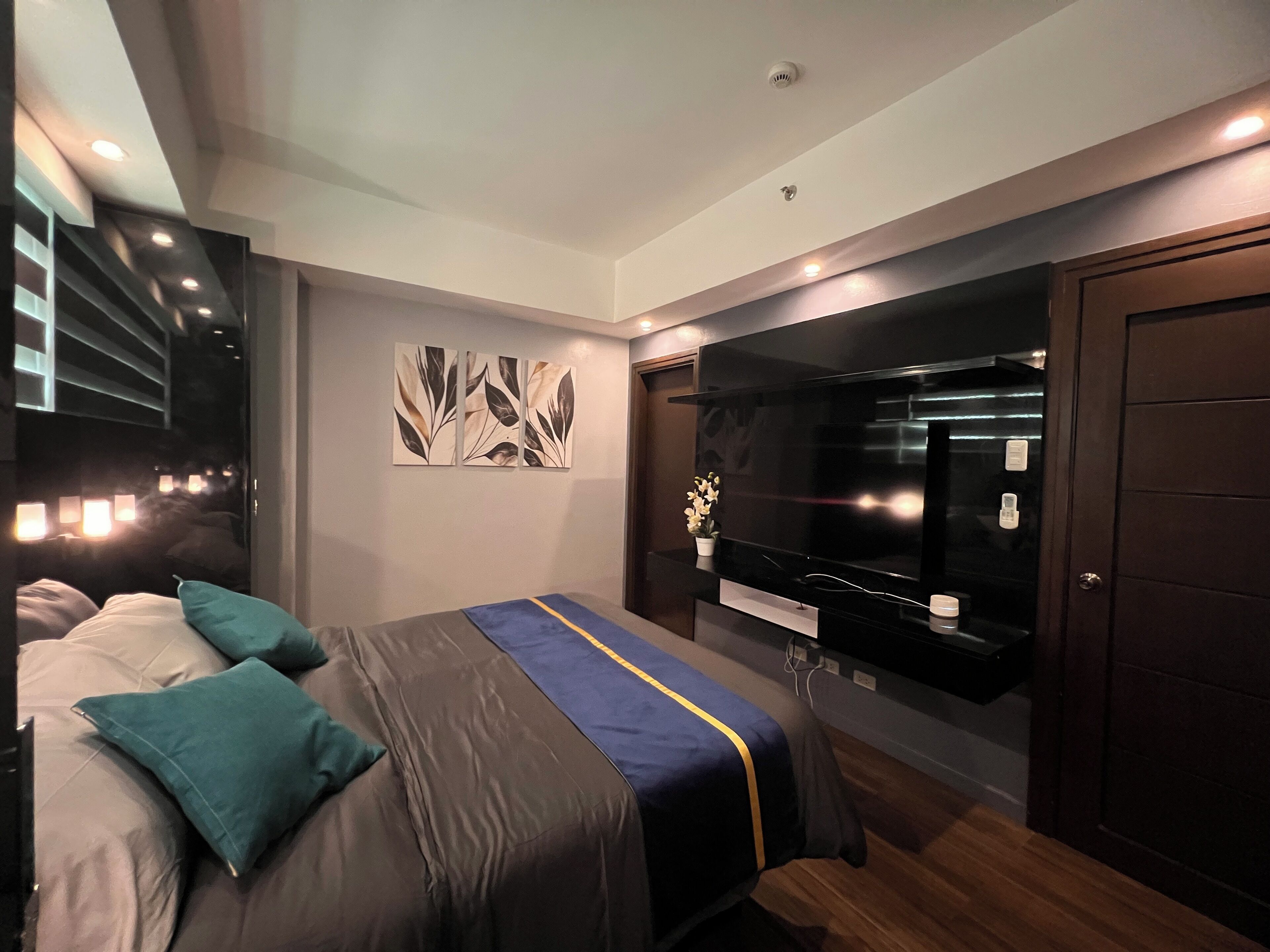 A modern bedroom with a bed, a large flat-screen TV, and a wardrobe.