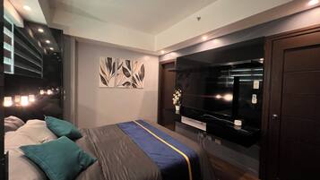 A modern bedroom with a bed, a large flat-screen TV, and a wardrobe.