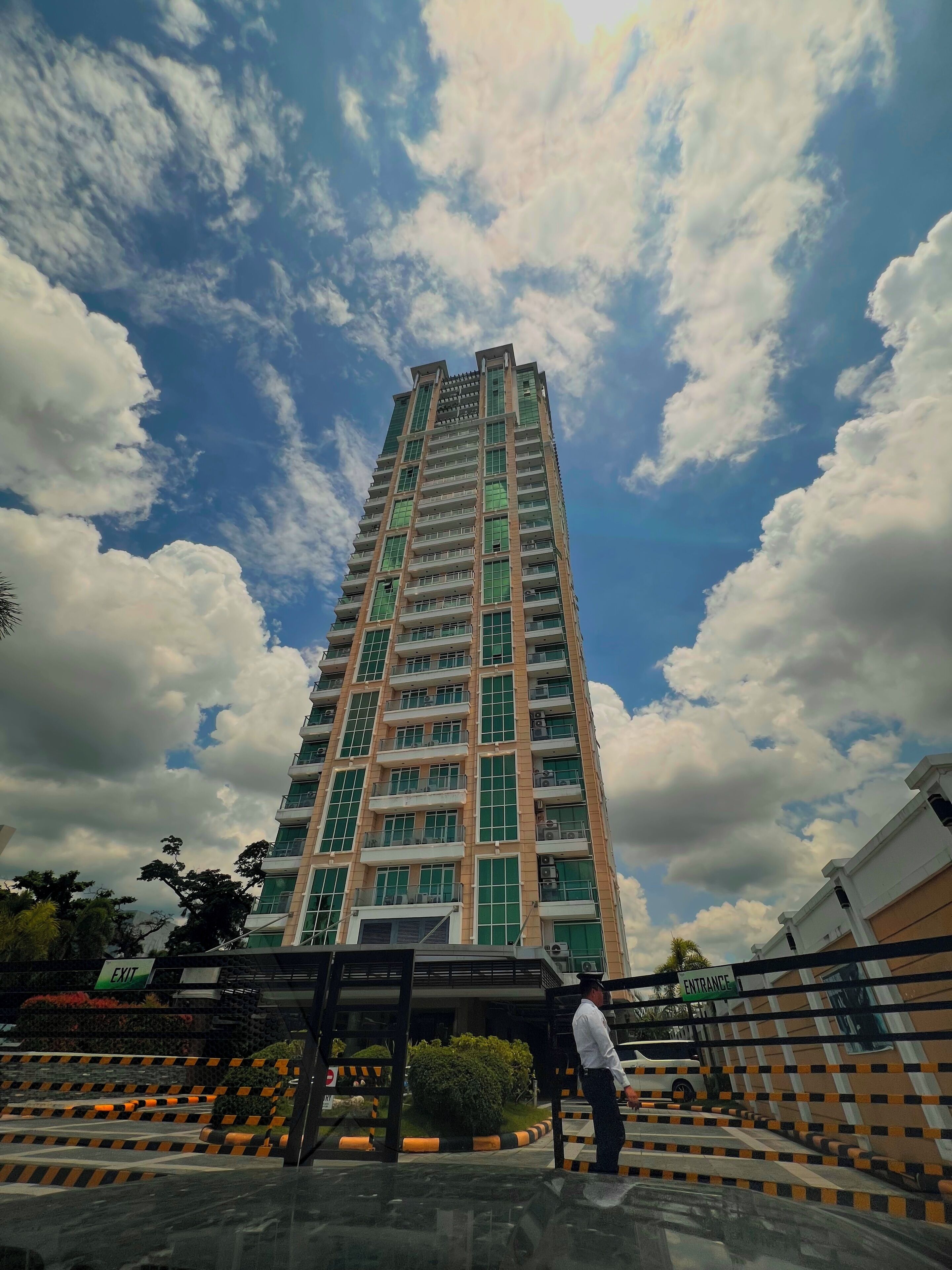 A tall residential building with multiple balconies and a gated entrance.