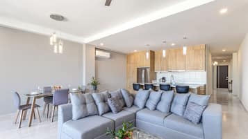 A modern living room with a sectional sofa, dining area, and kitchen.