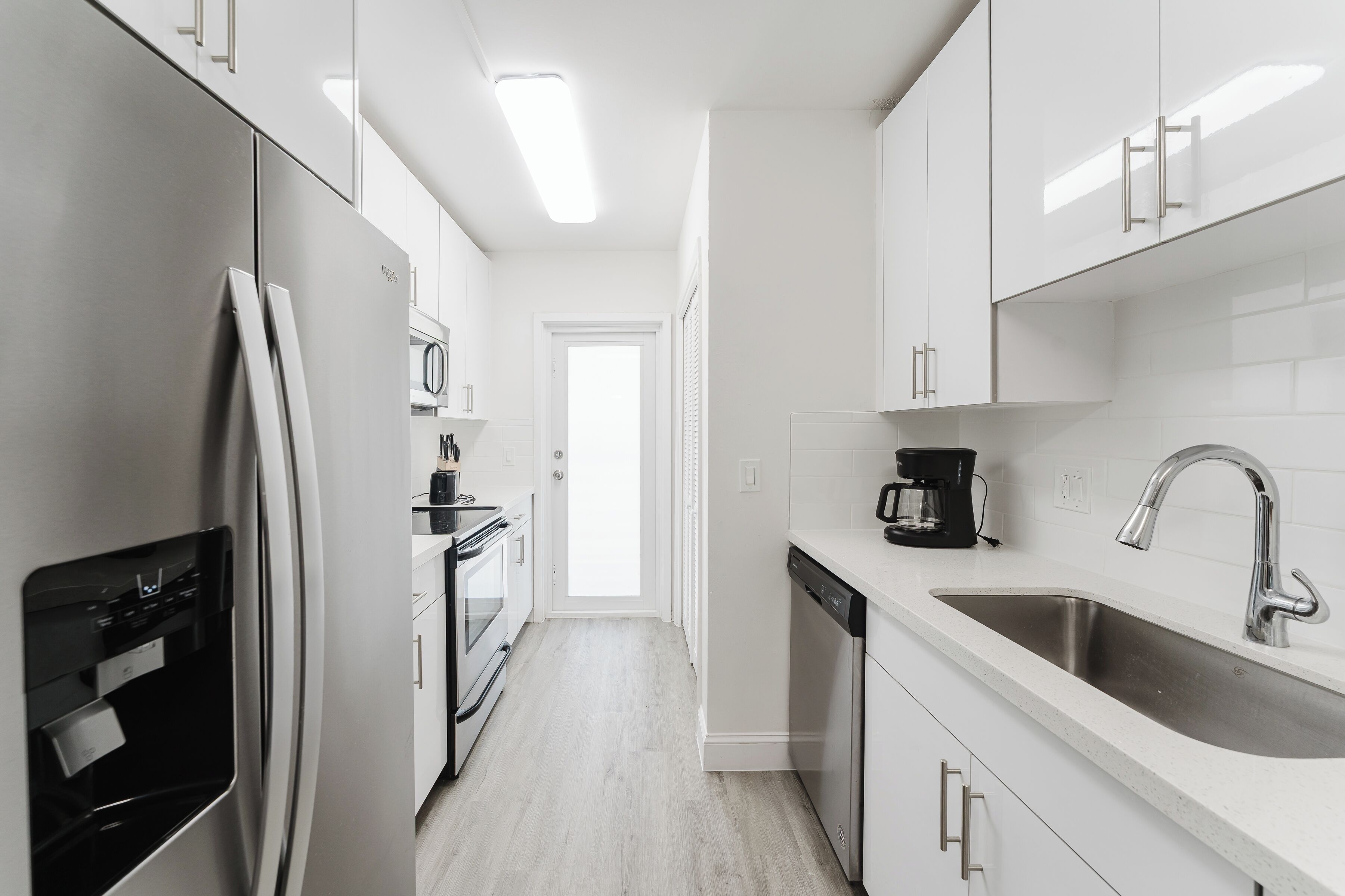 A modern kitchen with white cabinets, stainless steel appliances, and a dishwasher.