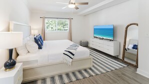 A bedroom with a bed, a television, a ceiling fan, a window with curtains, and a mirror. - Boca Waterfront Oasis: Walk to Beach + Pool, Hot Tub, Gym (Boca Raton)