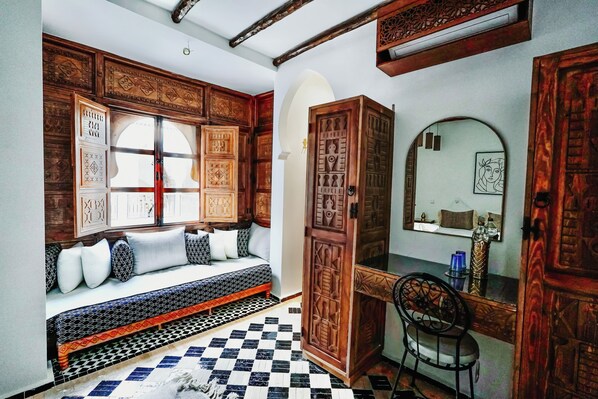 A traditional room with a wooden bench, a mirror, and a checkered floor.