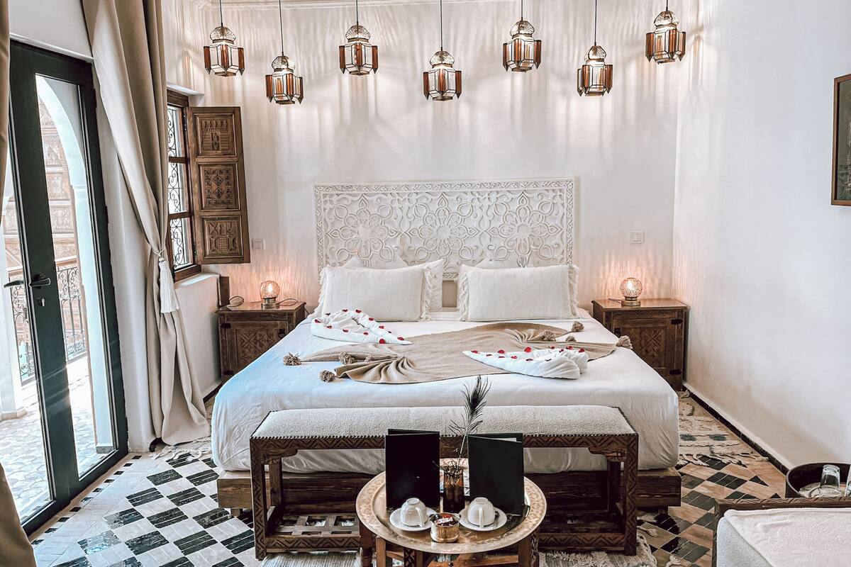 Ein geräumiges Schlafzimmer mit einem großen Bett, mehreren Nachttischen, einem kleinen Tisch mit Lampe und hängenden Laternen.
