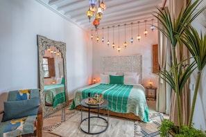 Ein Zimmer mit einem Bett, einem Stuhl, einem Tisch mit Tablett und Hängeleuchten.