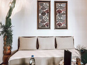 A bed with three pillows, a water bottle, and a magazine on a table. There are two framed wall art pieces above the bed. - Riad Nelia Signature (Marrakech)