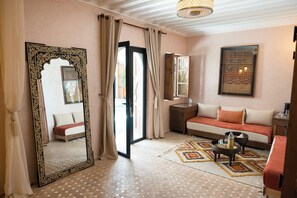 A room with a large ornate mirror, a sofa, a small table, and a patterned rug.