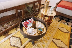 A wooden side table with a tray holding teacups, a decorative vase, and a bowl of blue candies. - Riad Nelia Signature (Marrakech)