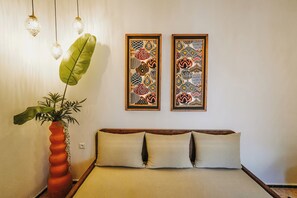 A bedroom with a bed, a large potted plant, and two framed wall art pieces. - Riad Nelia Signature (Marrakech)