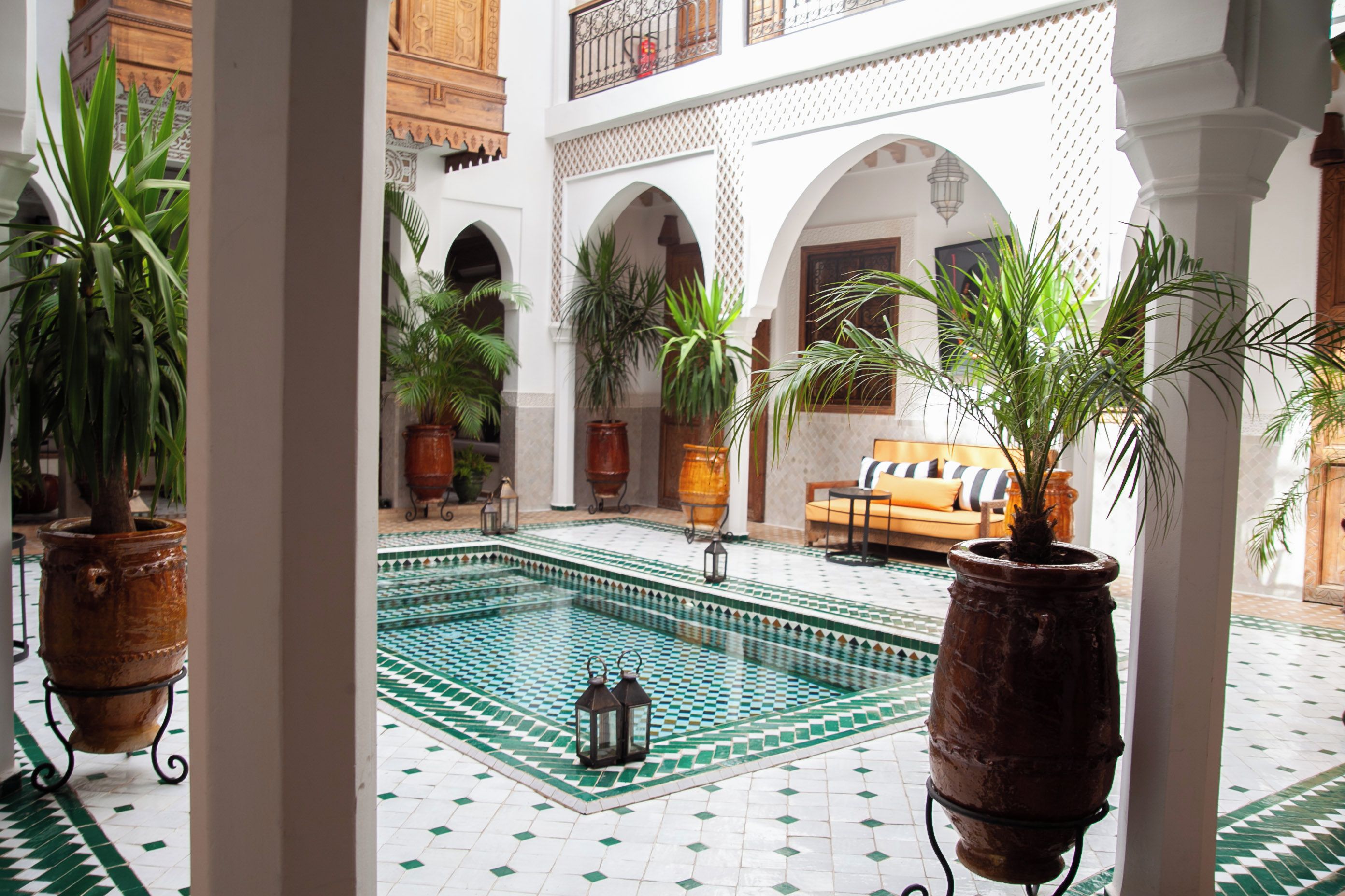A courtyard with a pool, potted plants, and a sofa.