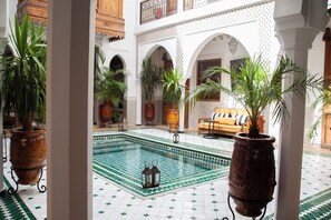 Ein Innenhof mit Pool, Topfpflanzen und einer Couch.