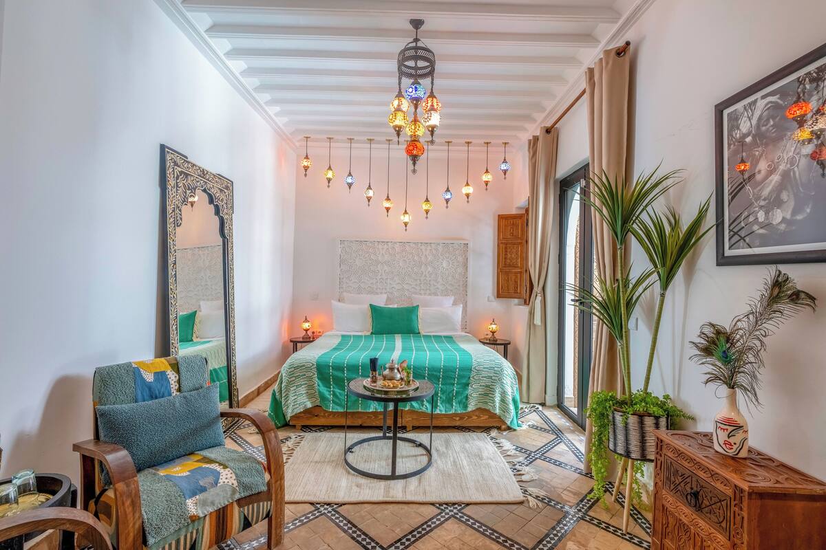 Ein gemütliches Schlafzimmer mit Bett, Sessel, Tisch und einer Pendelleuchte.