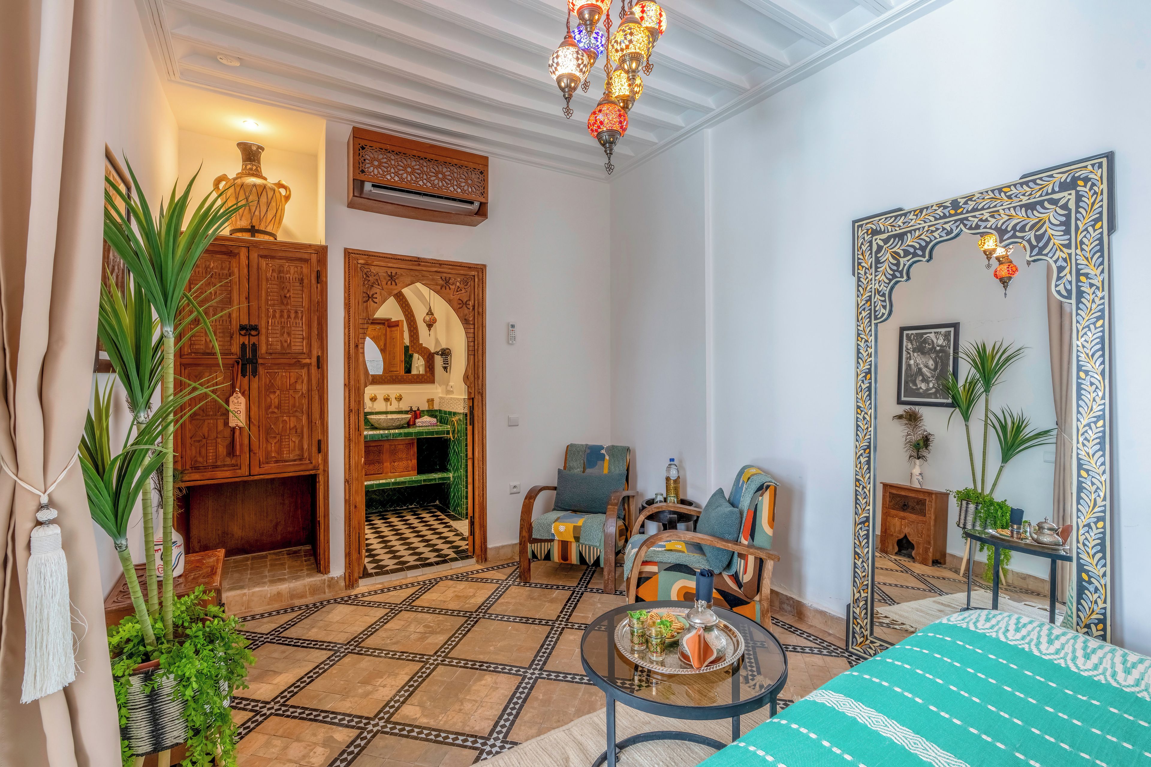 A room with a checkered floor, wooden furniture, a mirror with a decorative frame, and hanging lamps.