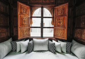 Ein Zimmer mit großem Fenster, Holzvertäfelung und einer Couch mit gemusterten Kissen.