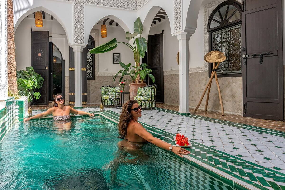 Ein Poolbereich mit gefliestem Boden, Bögen und Kübelpflanzen.