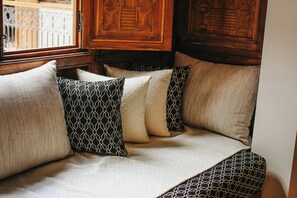 A bed with patterned pillows and a wooden headboard. - Riad Nelia Signature (Marrakech)