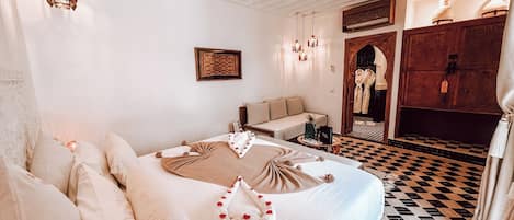 Una habitación de hotel con una cama grande, un sofá, una mesita y suelo a cuadros.