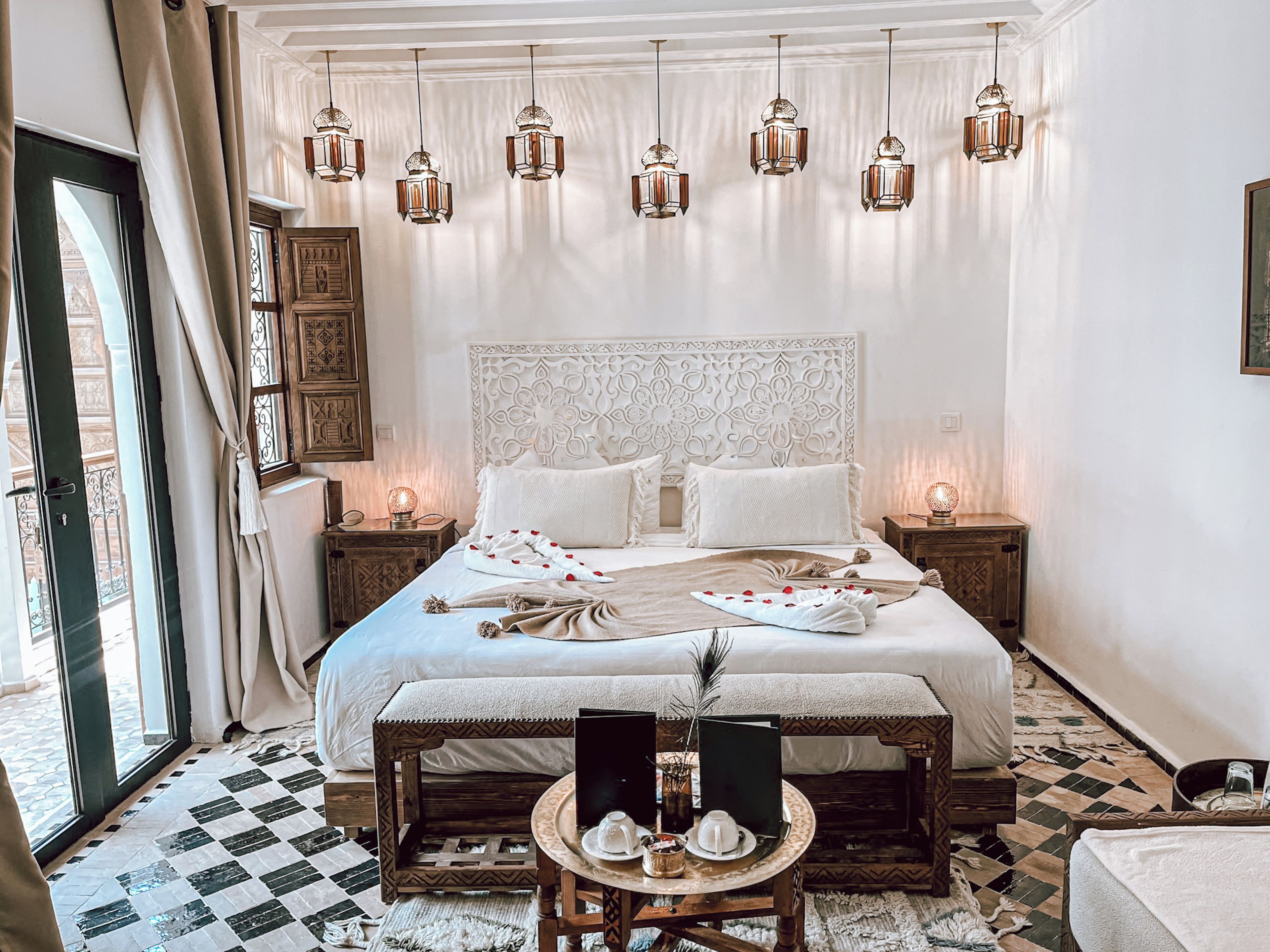 Un dormitorio amplio con una cama grande, varios mesitas de noche, una pequeña mesa con lámpara y faroles colgantes.