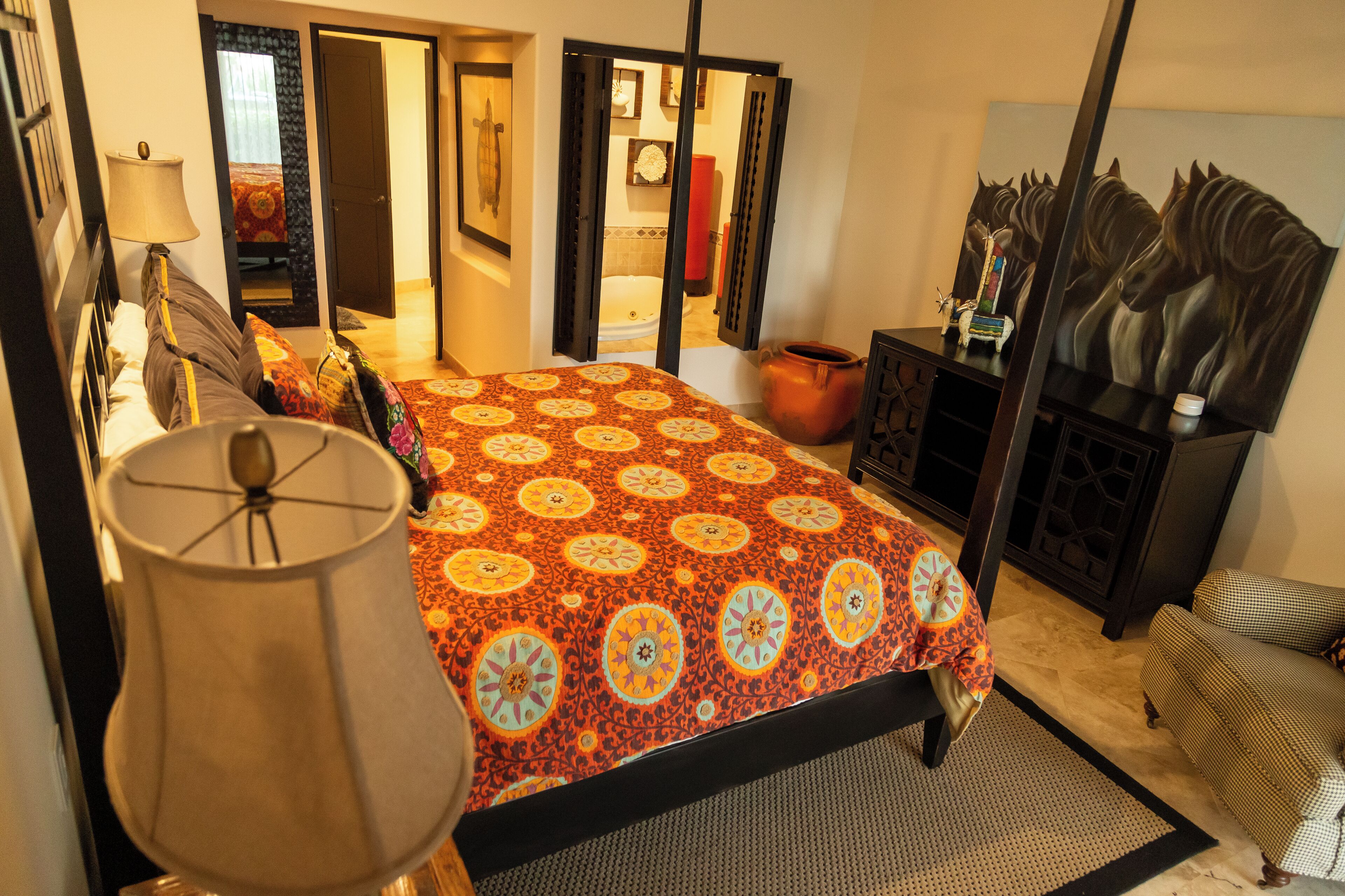 A bedroom with a bed, a nightstand, a lamp, a dresser, and a mirror.