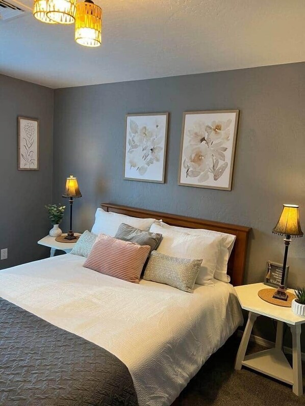 A neatly arranged bedroom with a bed, two bedside tables, and wall-mounted lamps.