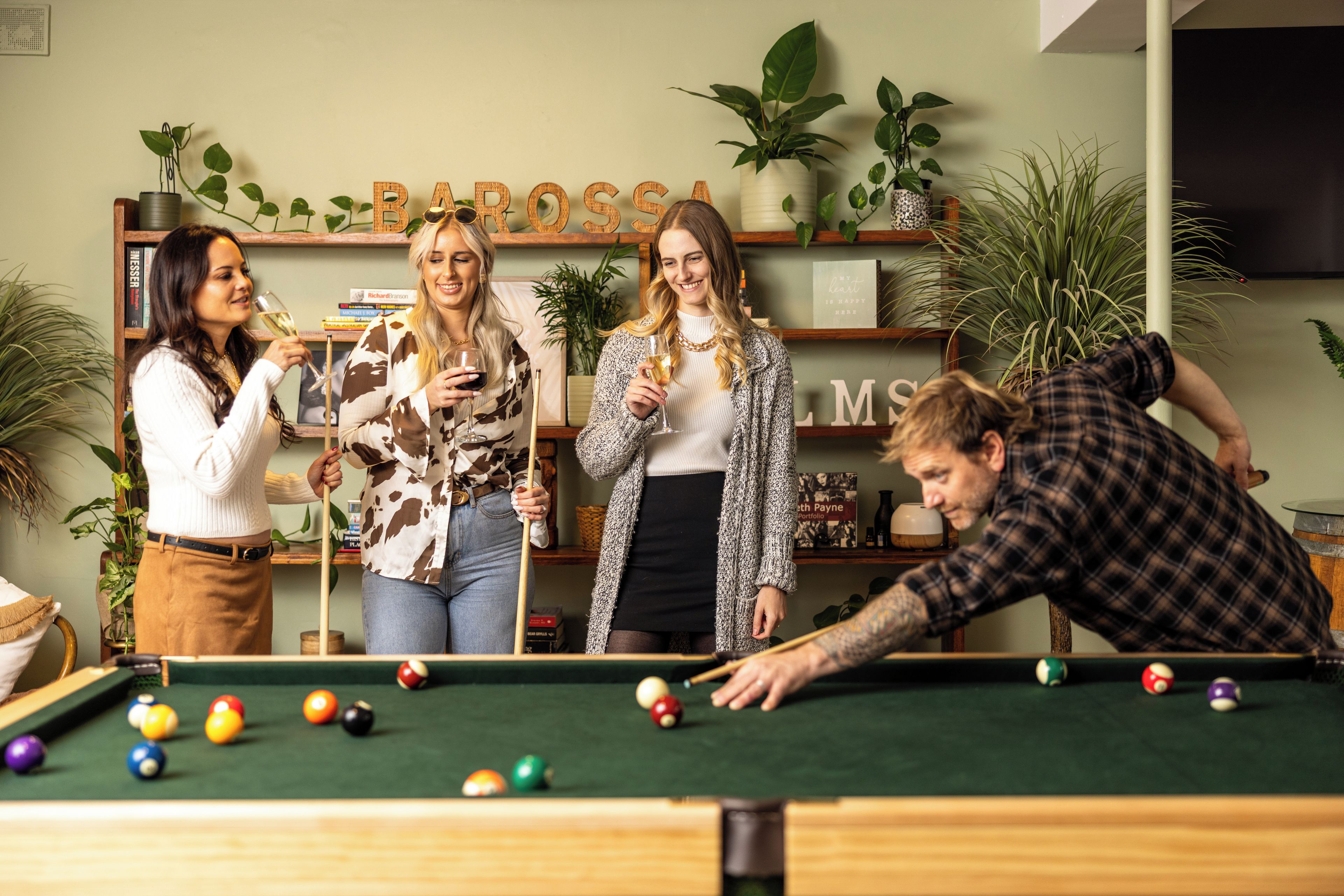 Ein Billardtisch mit Kugeln, eine Person beim Spielen und vier Personen, die zusehen.