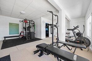 Ein Fitnessraum mit Trainingsgeräten, einer Bank und einem Laufband.