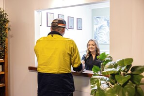 A reception area with a wooden counter, framed certificates on the wall, and a potted plant. - Barossa Palms Motel (Nuriootpa)
