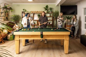 A pool table in a room with shelves of books and plants. - Barossa Palms Motel (Nuriootpa)