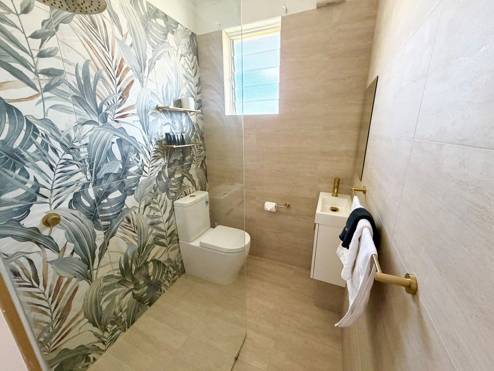A bathroom with a toilet, a sink, a towel rack, and a shower area.
