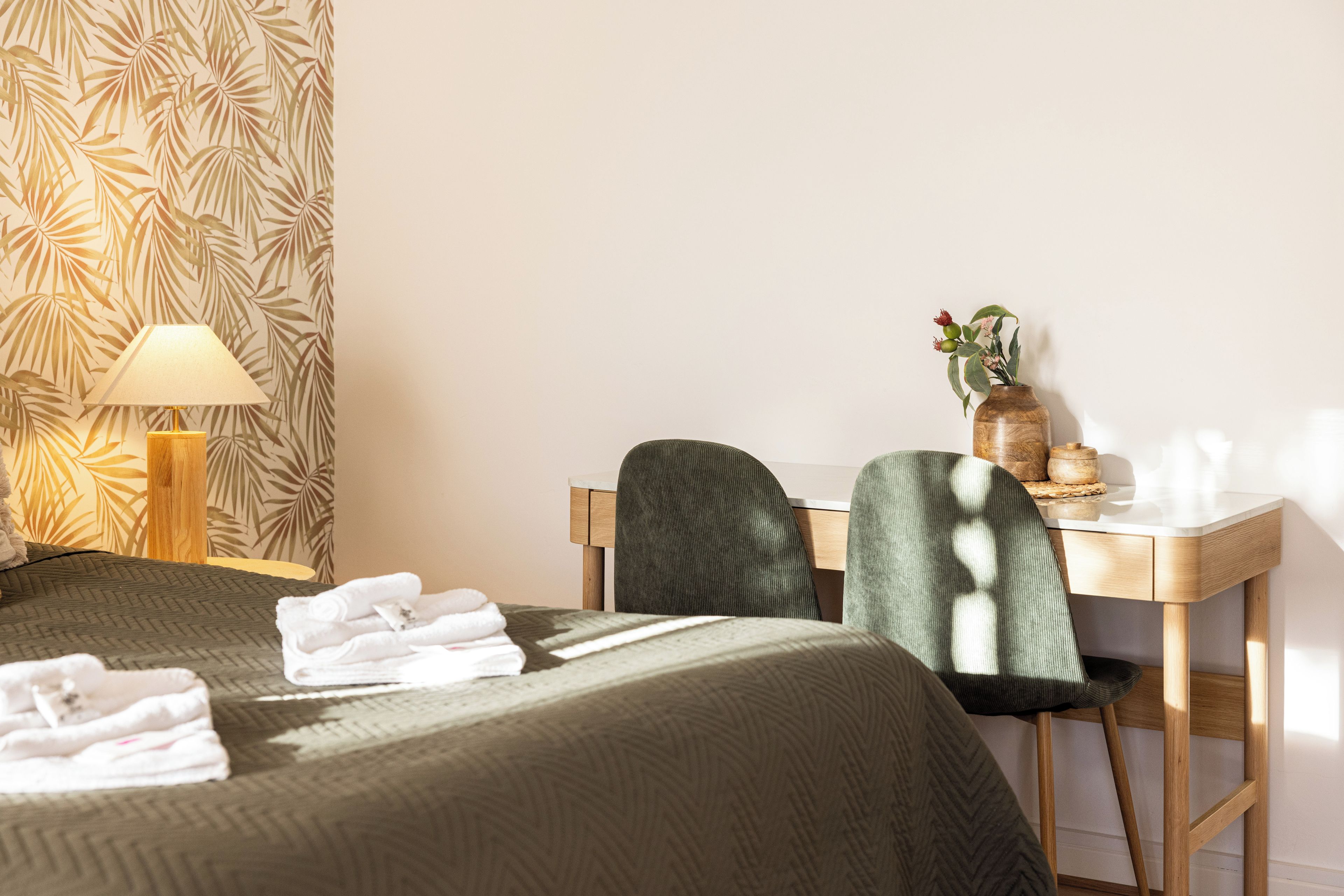 Ein Hotelzimmer mit einem Bett, einem Schreibtisch, einem Stuhl, einer Lampe und einer Vase mit Blumen.