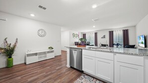 Una cocina moderna con armarios blancos, lavavajillas de acero inoxidable y encimera de granito.