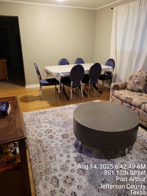 A dining area with a table and chairs, a sofa, and a patterned rug. - 4-Bedroom Retreat w/Modern Comforts & Local Charm! (Port Arthur)