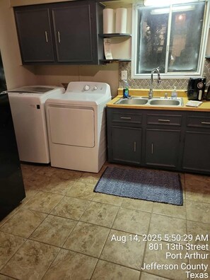 A kitchen with a washing machine, a sink, and cabinets. - 4-Bedroom Retreat w/Modern Comforts & Local Charm! (Port Arthur)