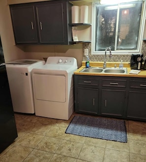 A kitchen with a washing machine, a sink, and cabinets. - 4-Bedroom Retreat w/Modern Comforts & Local Charm! (Port Arthur)