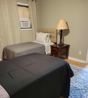 A hotel room with two beds, a nightstand, a lamp, and a window with curtains. - 4-Bedroom Retreat w/Modern Comforts & Local Charm! (Port Arthur)