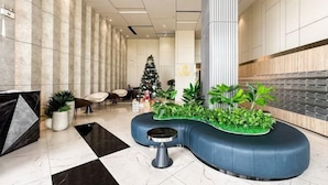 Eine moderne Lobby mit einer gebogenen Sitzecke, einem Weihnachtsbaum und einer großen Säule.