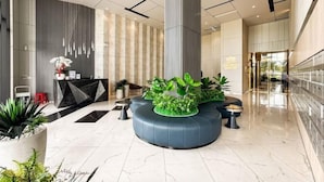 Eine moderne Lobby mit einer zentralen Sitzgruppe, einem Empfangsbereich und einer großen Säule.