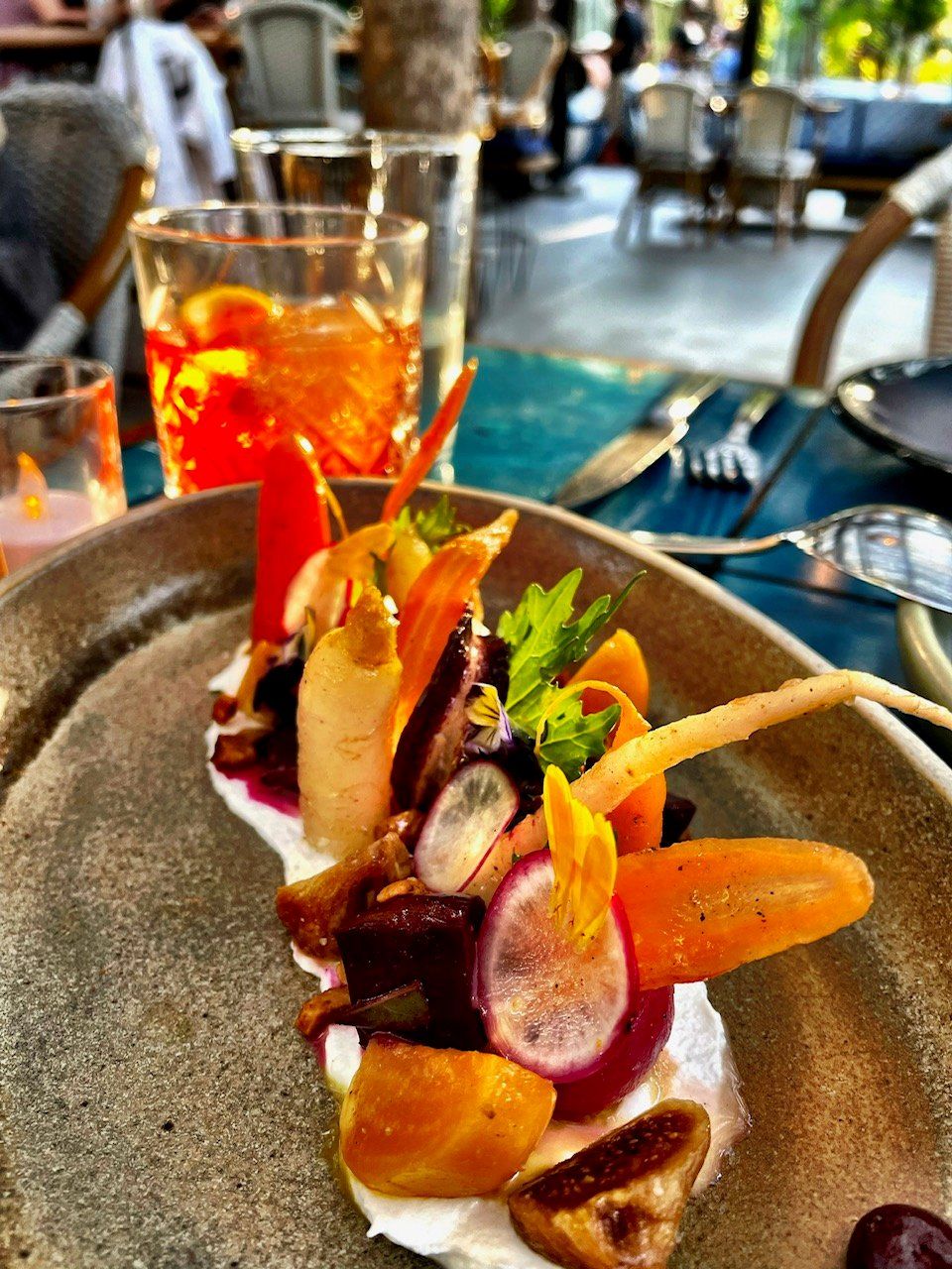 A dining table with a plate of food, a glass of drink, and a fork.